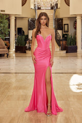 Woman in a pink evening gown standing in an elegant indoor setting.
